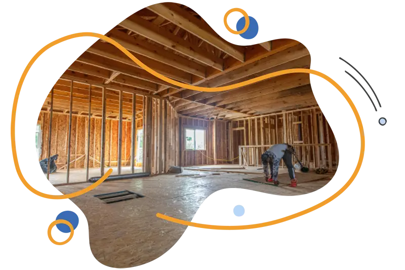 Construction site interior with wooden framing, featuring a worker laying flooring, highlighting modern building practices for energy-efficient homes.